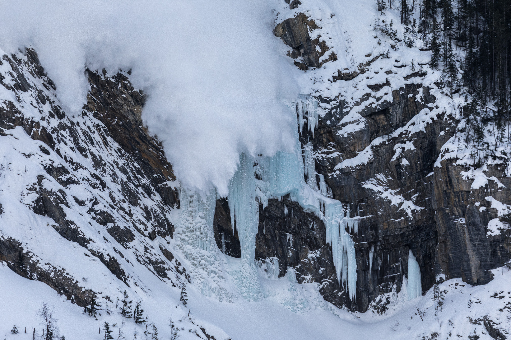 An avalanche descending over ice-climbing terrain at Pilsner Pillar in the Canadian Rockies