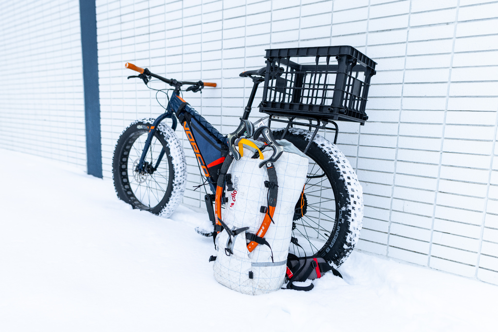 White climbing pack with two ice tools resting beside the bike, leaving its rear crate empty.