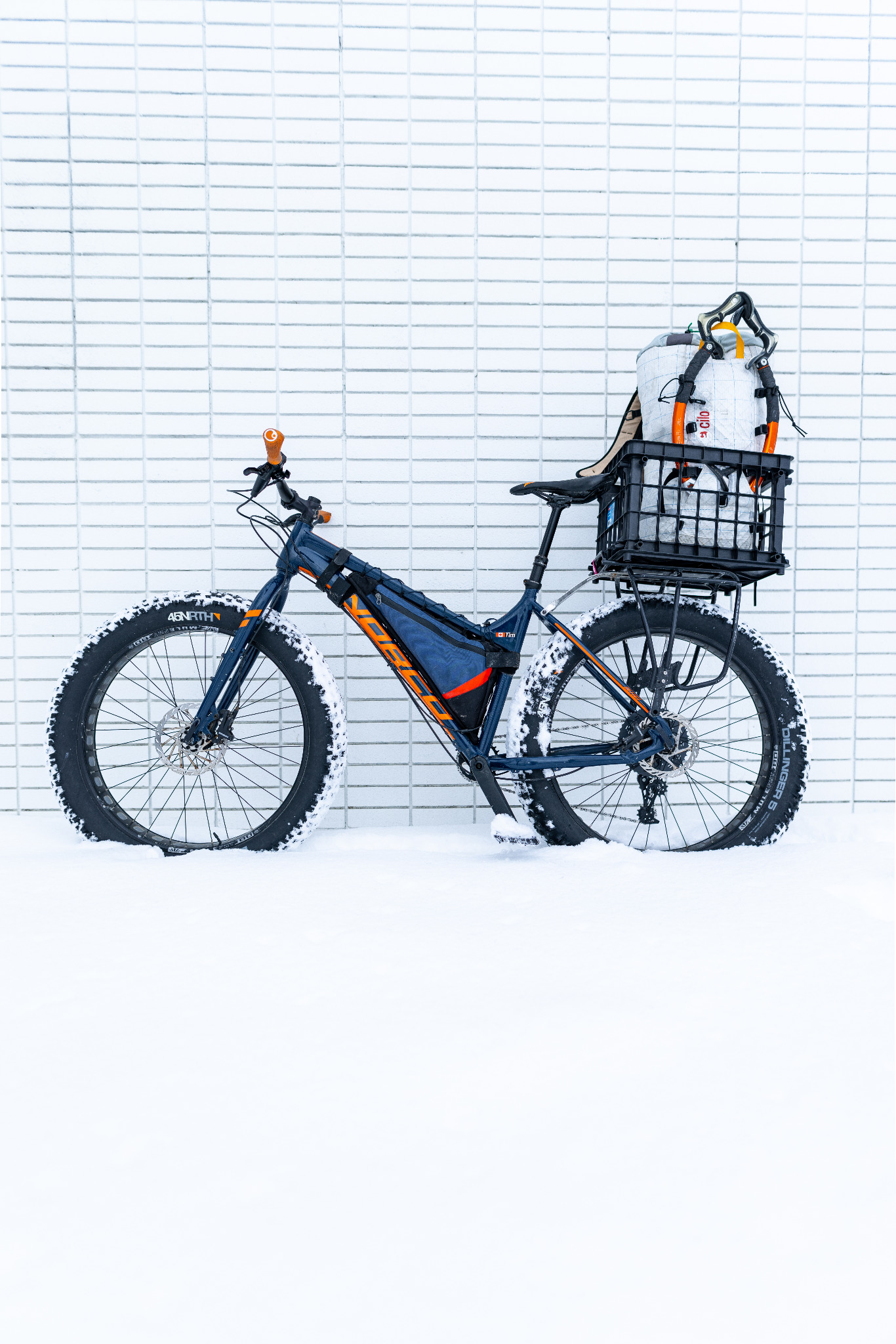 Side view of a fat bike carrying a white climbing pack and ice tools in a black rear crate.