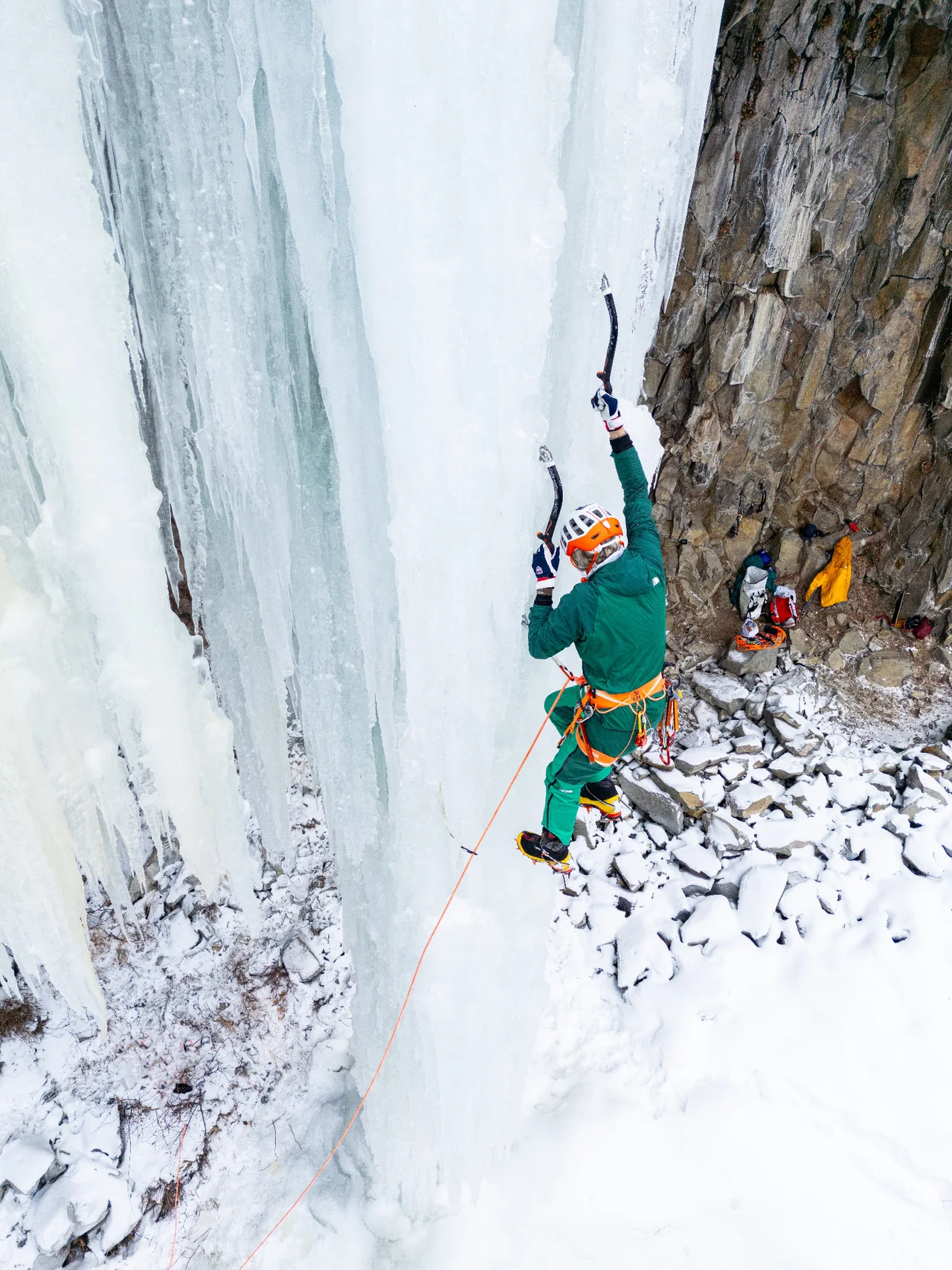 Elevated view of Conrad Anker reaching up the ice on Bingo Pillar.