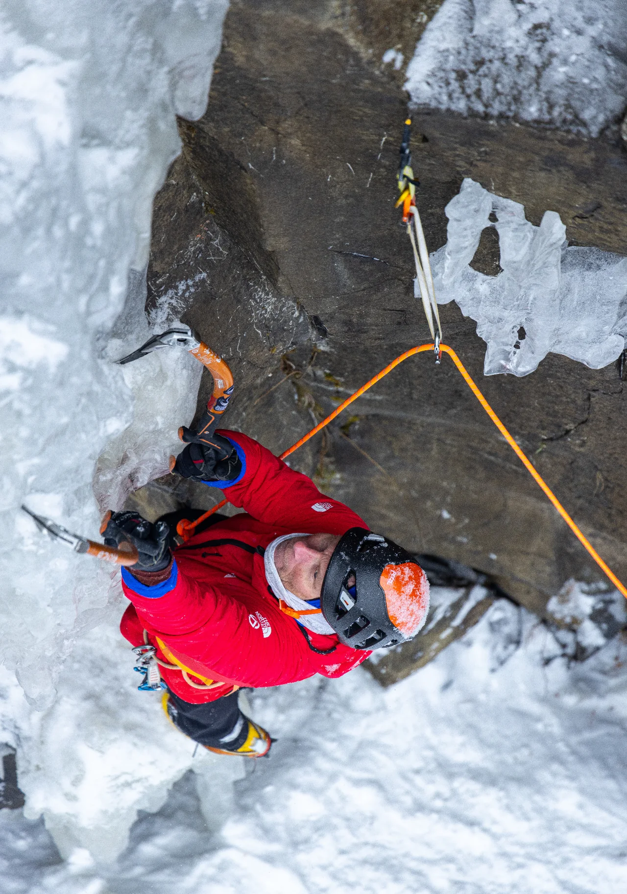 Overhead close-up of Conrad Anker climbing thin ice beside exposed rock on The Good Looking One.