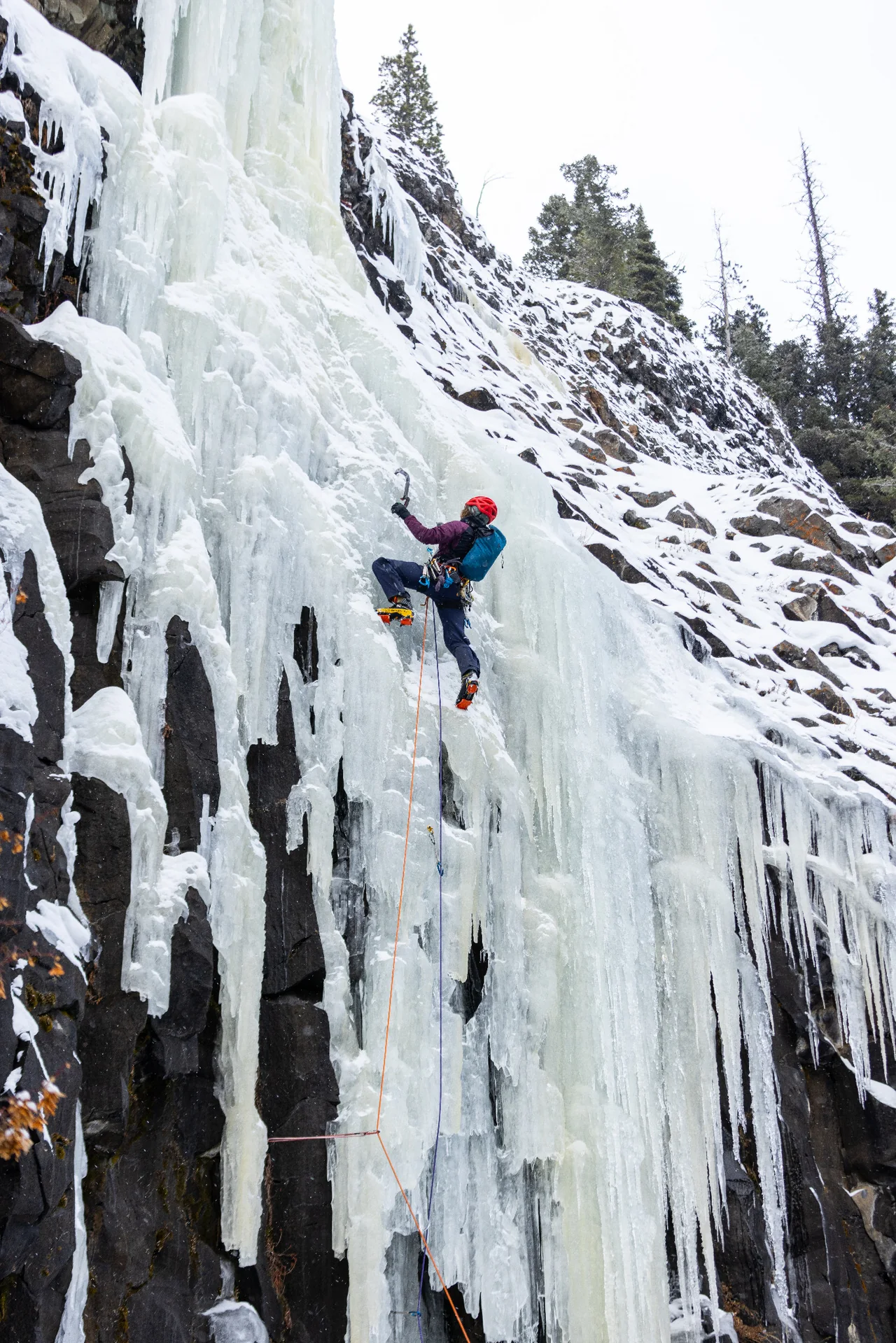 Lindsay Fixmer climbing The Good Looking One among long icicles and dark rock.